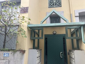 A building entrance with a green door, a mailbox, and a number sign indicating the address.