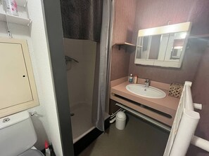 A bathroom with a shower, toilet, sink, and mirror.