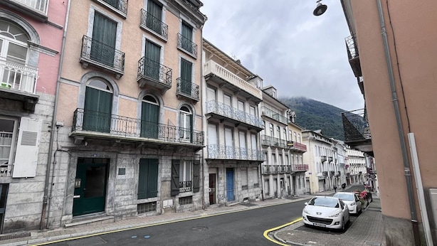 A street with historic buildings, a yellow curb, and parked cars. - Cauterets: Central T2 Apartment, 4-5 pers (Cauterets)