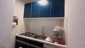 A compact kitchen with a gas stove, sink, and blue cabinets. - Cauterets: Central T2 Apartment, 4-5 pers (Cauterets)