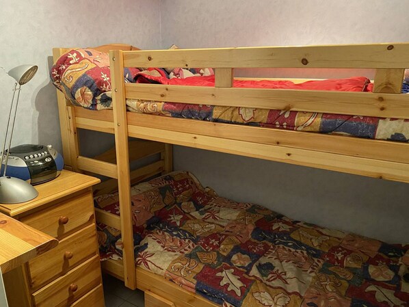 Una cama litera con escritorio y cajones, una lámpara y una radio.