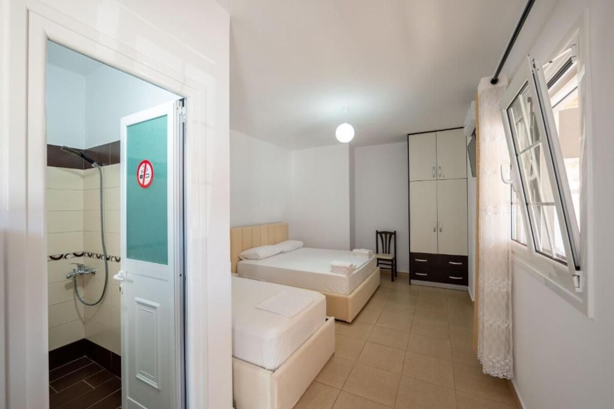 Quarto pequeno e limpo, com duas camas, um guarda-roupa e zona de chuveiro.