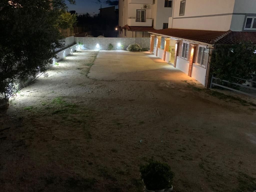 Una propiedad residencial con camino de entrada pavimentado, un pequeño jardín y una casa con techo de tejas.