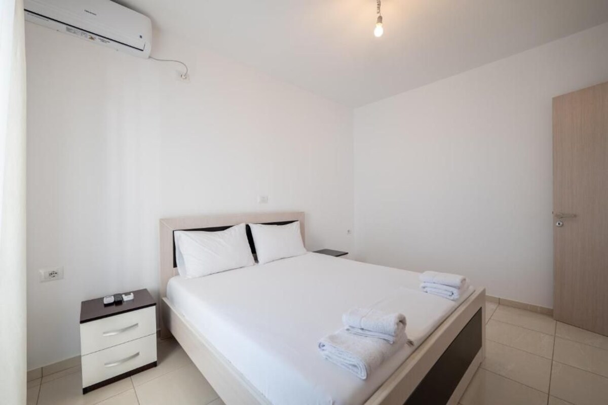 Un dormitorio limpio y moderno con una cama individual, mesitas de noche, un armario y un equipo de aire acondicionado.