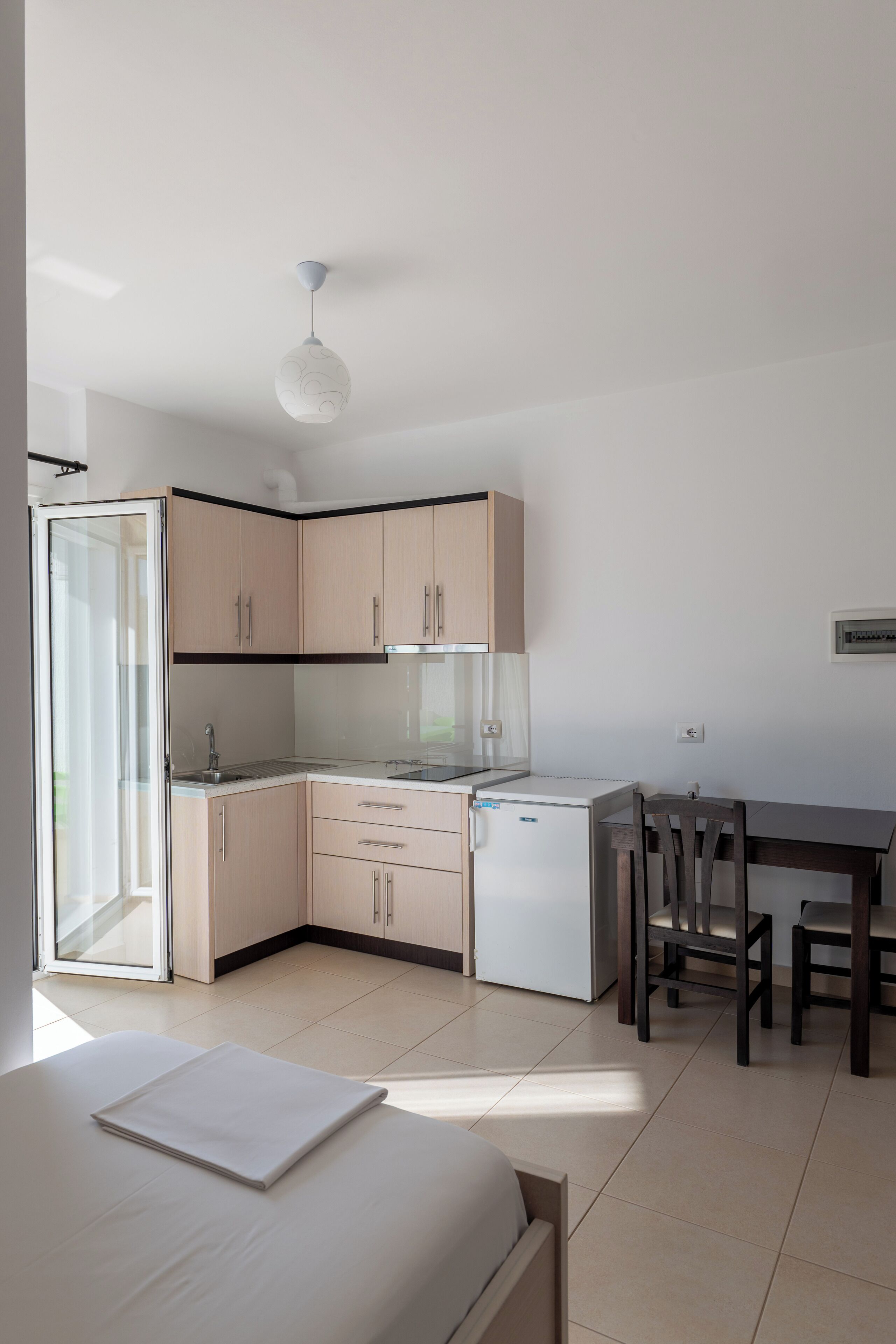 A modern kitchen with light wood cabinets, a white countertop, and a built-in dishwasher.