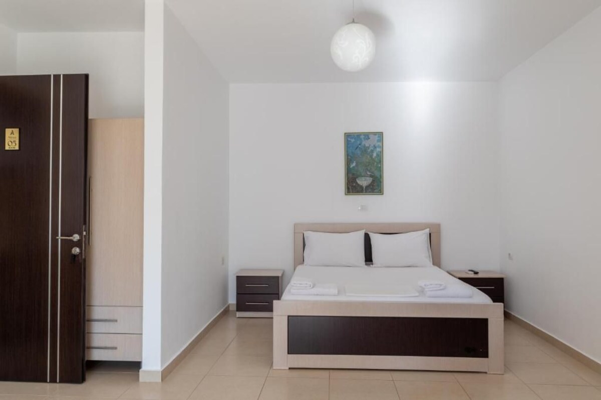 Un dormitorio con cama, mesitas de noche, armario y un cuadro en la pared.