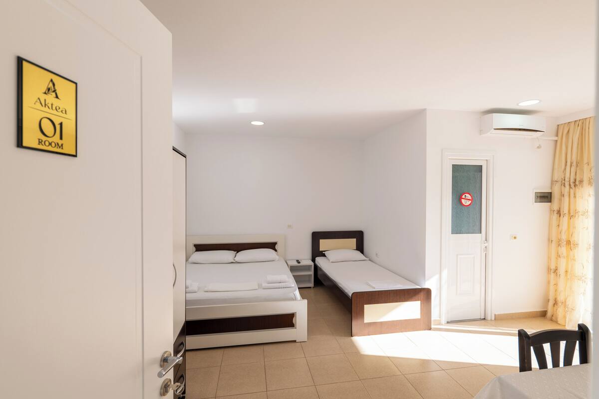 A hotel room with two beds, a table, and a chair.