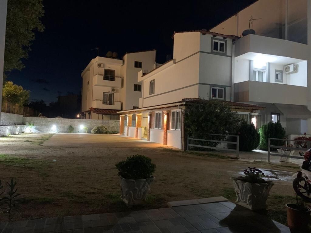 A residential building with multiple floors, a paved driveway, and outdoor lighting.