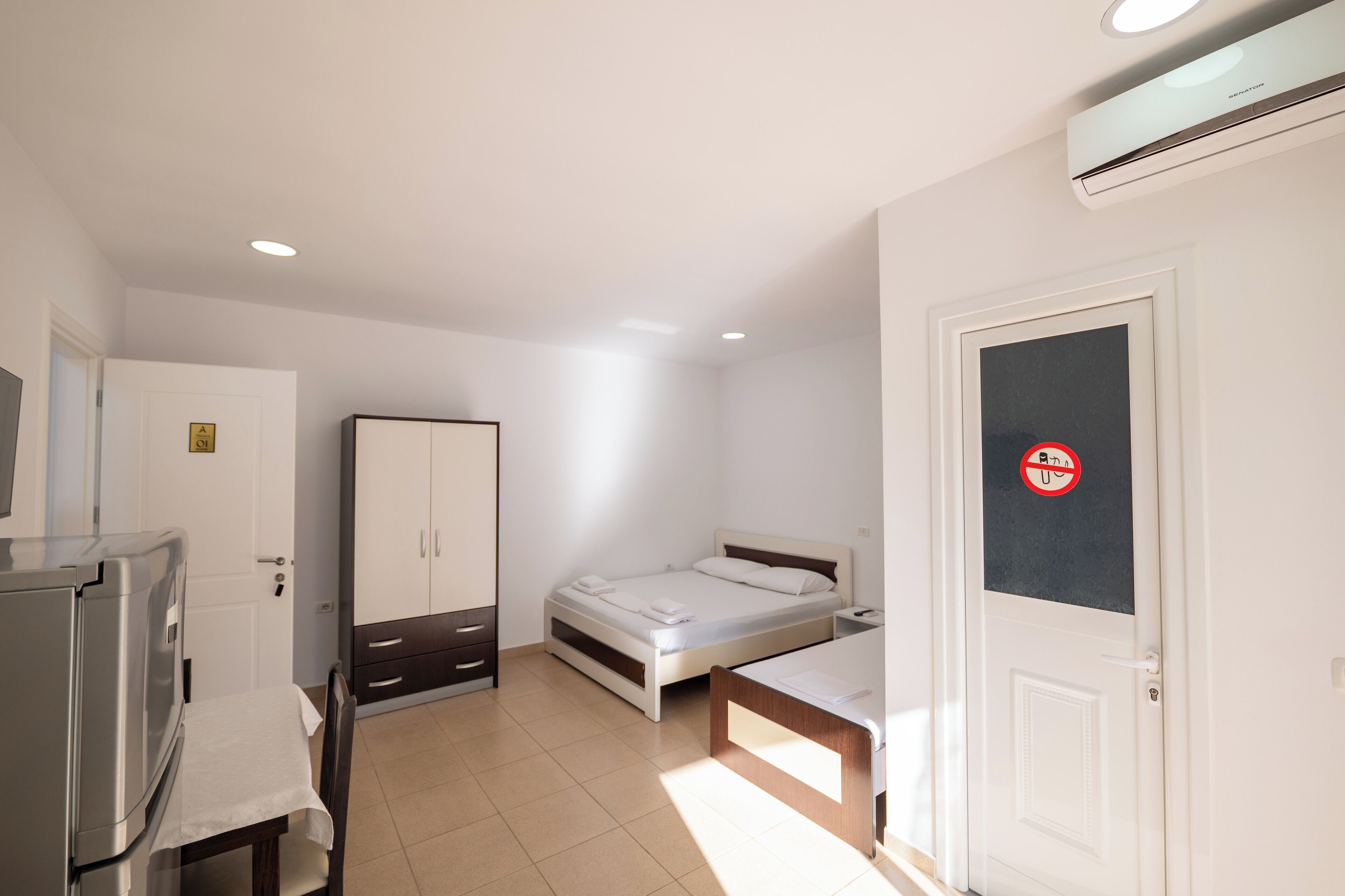 Un dormitorio con cama, escritorio, armario y una puerta con un cartel de no fumar.
