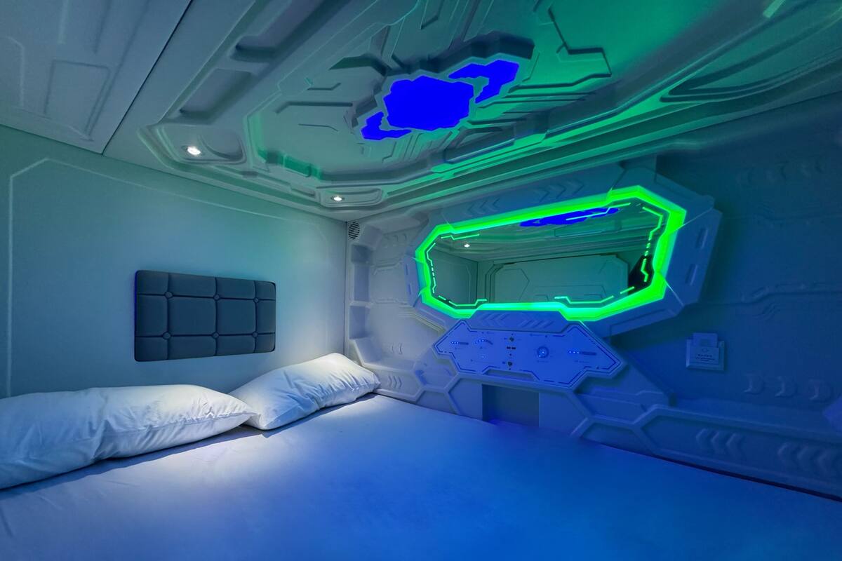 A room with a bed, a headboard, and a wall with a geometric design.
