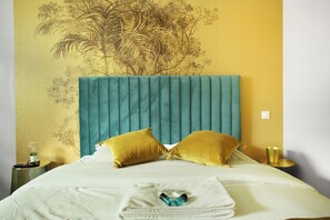 A hotel room with a large bed, two pillows, a bedside table with a lamp, and a wall with a floral mural. - Charming & New Studio Center of Paris (Paris)