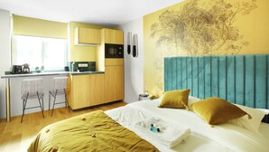 Ett modernt hotellrum med en säng, ett skrivbord och ett litet kök.