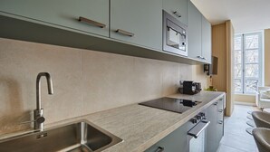 A modern kitchen with a stainless steel sink, a built-in oven, and a coffee machine. - Sublim Apartement in the Center of Paris/le Marais (Paris)