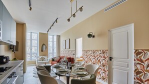 A modern kitchen with a dining area, featuring a large table set for six, a built-in oven, and a window with a view of the city. - Sublim Apartement in the Center of Paris/le Marais (Paris)