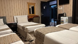 Habitación de hotel con dos camas individuales, un escritorio con silla, un espejo, un armario, un refrigerador y una televisión.