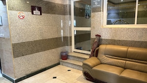 Un área de recepción con un cartel de zona de oración, un letrero para el cuarto de cámaras y un sofá de cuero.