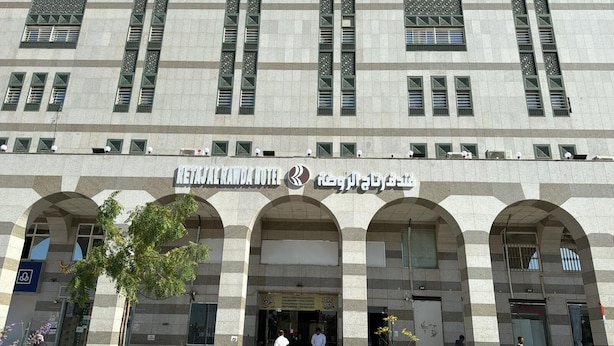 Un edificio con un letrero que dice "RETAJ AL RAWDA HOTEL" y una entrada en arco.