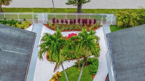 A rooftop garden with a pathway, palm trees, and various plants. - Stylish Miami Studio | Parking+Gym | Near Aventura (Miami)