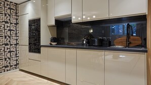 Una cocina moderna con armarios blancos, encimera negra y un salpicadero decorado.