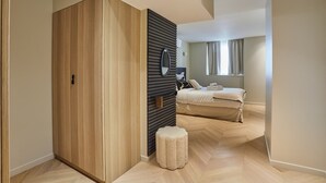 Un dormitorio moderno con un armario de madera, un taburete pequeño y una cama con cabecero.