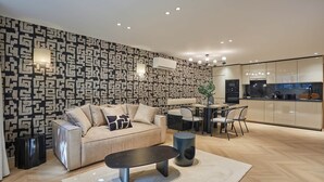 Una sala de estar moderna con una pared estampada, un sofá, una mesa de centro y un comedor con sillas y una mesa.