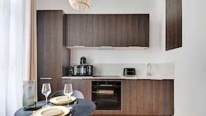 Una cucina moderna con mobili in legno scuro, forno a incasso, macchina del caffè e tostapane.