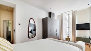 Una camera da letto moderna con un letto grande, un armadio, uno specchio e un televisore.