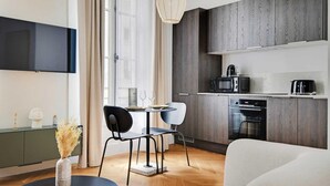 Una cucina moderna con mobili in legno scuro, forno a microonde integrato e macchina da caffè. C'è un'area pranzo con un tavolo rotondo e due sedie.