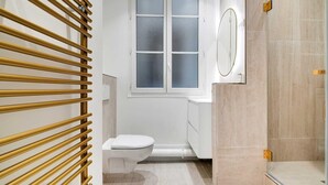 Un bagno moderno con il water, uno spazio doccia in vetro e una zona doccia con listelli di legno.