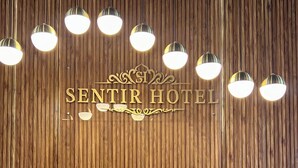 Eine Holzwand mit dem Schriftzug "SENTIR HOTEL" und dekorativen Elementen.