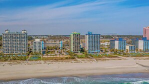 A beachfront hotel with multiple high-rise buildings, a sandy beach, and ocean waves.