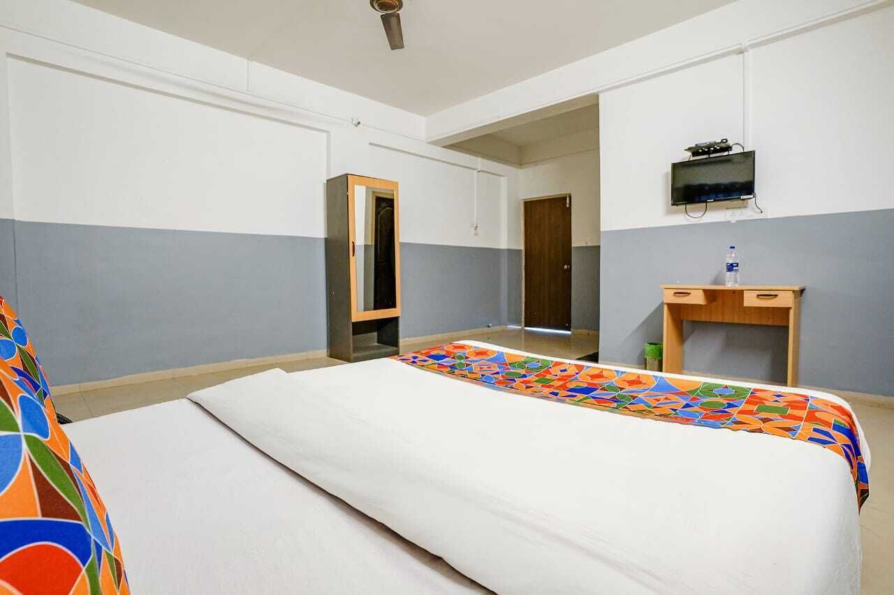 A hotel room with a bed, a desk, a television, and a mirror.