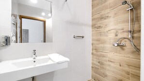 Un baño moderno con un lavamanos blanco, un espejo y una ducha con pared de madera.