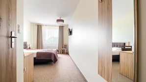 Habitación de hotel con cama, escritorio, silla, televisor y un espejo grande.