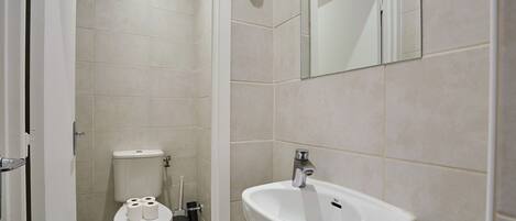 A bathroom with a toilet, sink, and mirror.