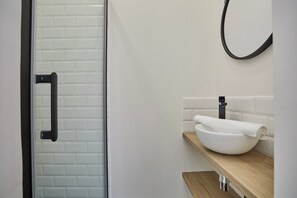 Bathroom features a glass shower enclosure, white sink, and black faucet.
