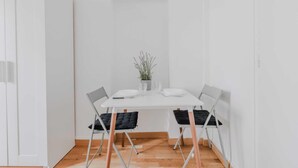 A minimalist dining area with a white table, two chairs, and a small potted plant. - Lovely Studio for 2 People - Levallois-perret (Levallois-Perret)