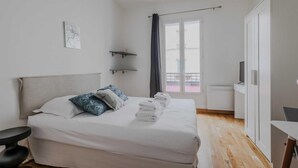 A bedroom with a bed, a desk, a chair, a TV, and a balcony. - Lovely Studio for 2 People - Levallois-perret (Levallois-Perret)