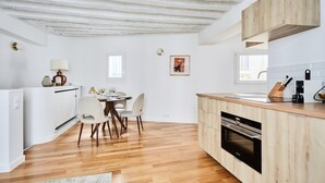A modern kitchen with wooden cabinets, a dining area with chairs, and a built-in oven.