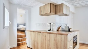 A modern kitchen with wooden cabinets, a central island, and a built-in oven.