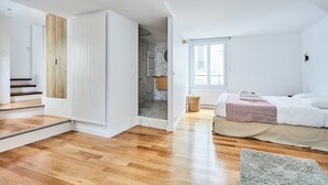 A bedroom with a bed, a window, and a wooden floor.