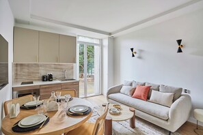 A modern living room with a sofa and a dining table set for four. - Charming Flat Jardin du Luxembourg Montparnasse (Paris)