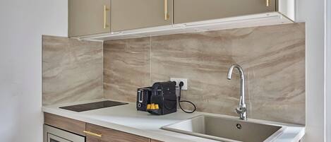 A kitchen with two sinks, a built-in oven, and a coffee machine.