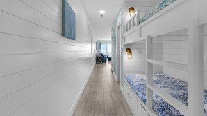 A narrow hallway with bunk beds on one side and a seating area with a table and chairs on the other.
