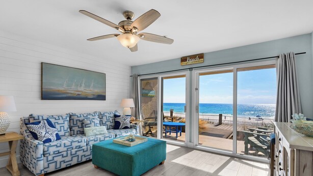 A living room with a view of the beach, a ceiling fan, and a sign that says "beach".