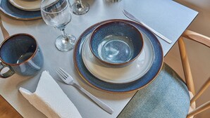 A dining table set with blue plates, a white bowl, a clear glass, a white napkin, and a fork. - Amazing Studio Le Marais (Paris)
