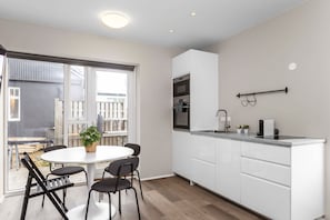 A modern kitchen with white cabinets, a round dining table with chairs, and a large window.
