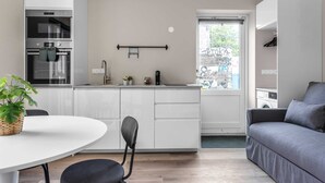 A modern kitchen with white cabinets, a built-in oven, and a window with a view of the street. - Freyjugata Apartments - Central Studio (Reykjavík)
