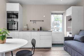 A modern kitchen with white cabinets, a built-in oven, and a window with a view of the street.