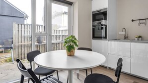 A modern kitchen with white cabinets, a built-in oven, and a window overlooking a backyard. - Freyjugata Apartments - Central Studio (Reykjavík)